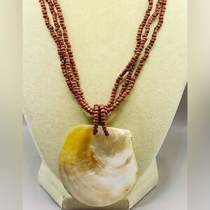 Handmade maroon seed bead multi strand necklace with a large shell pendant. Boho